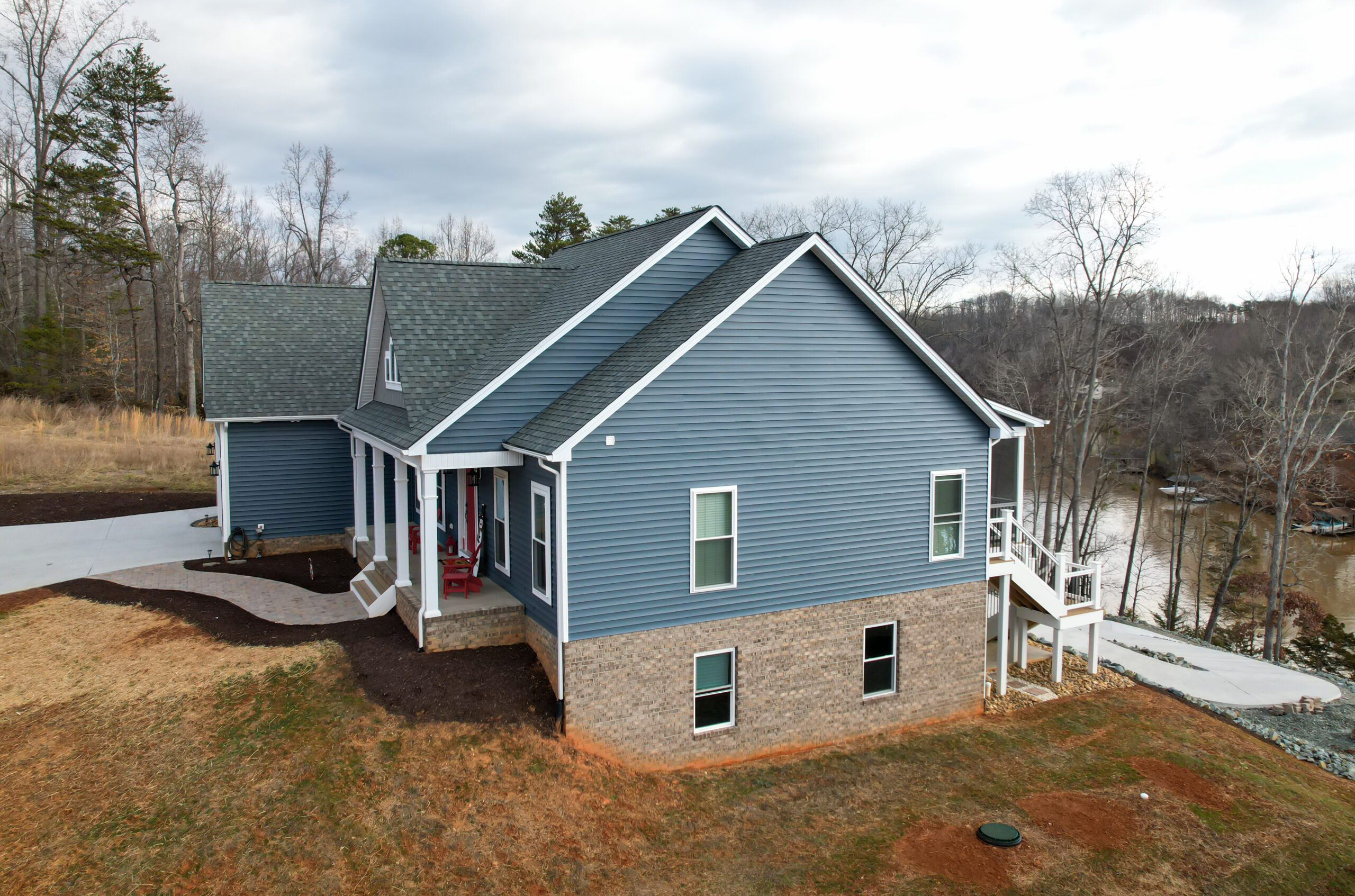 Custom lakefront home, entry side showing vinyl siding and stone veneer foundation transition
