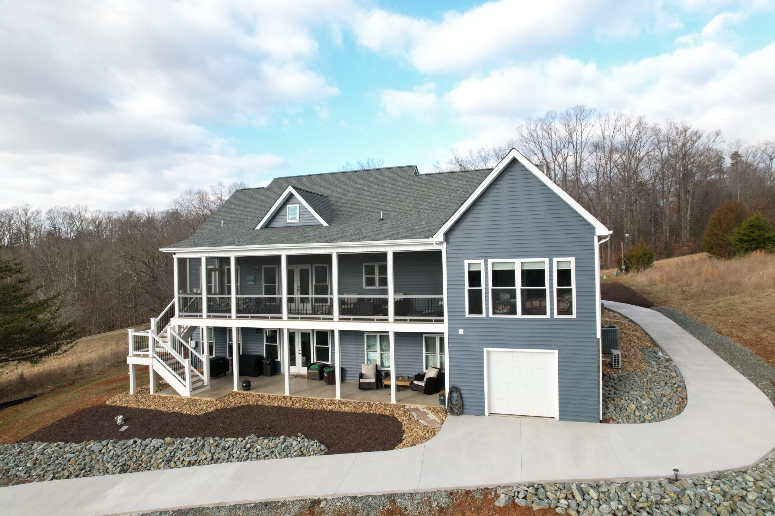 Lake side showing screened porch, walkout lower level with full-height windows, and lower garage